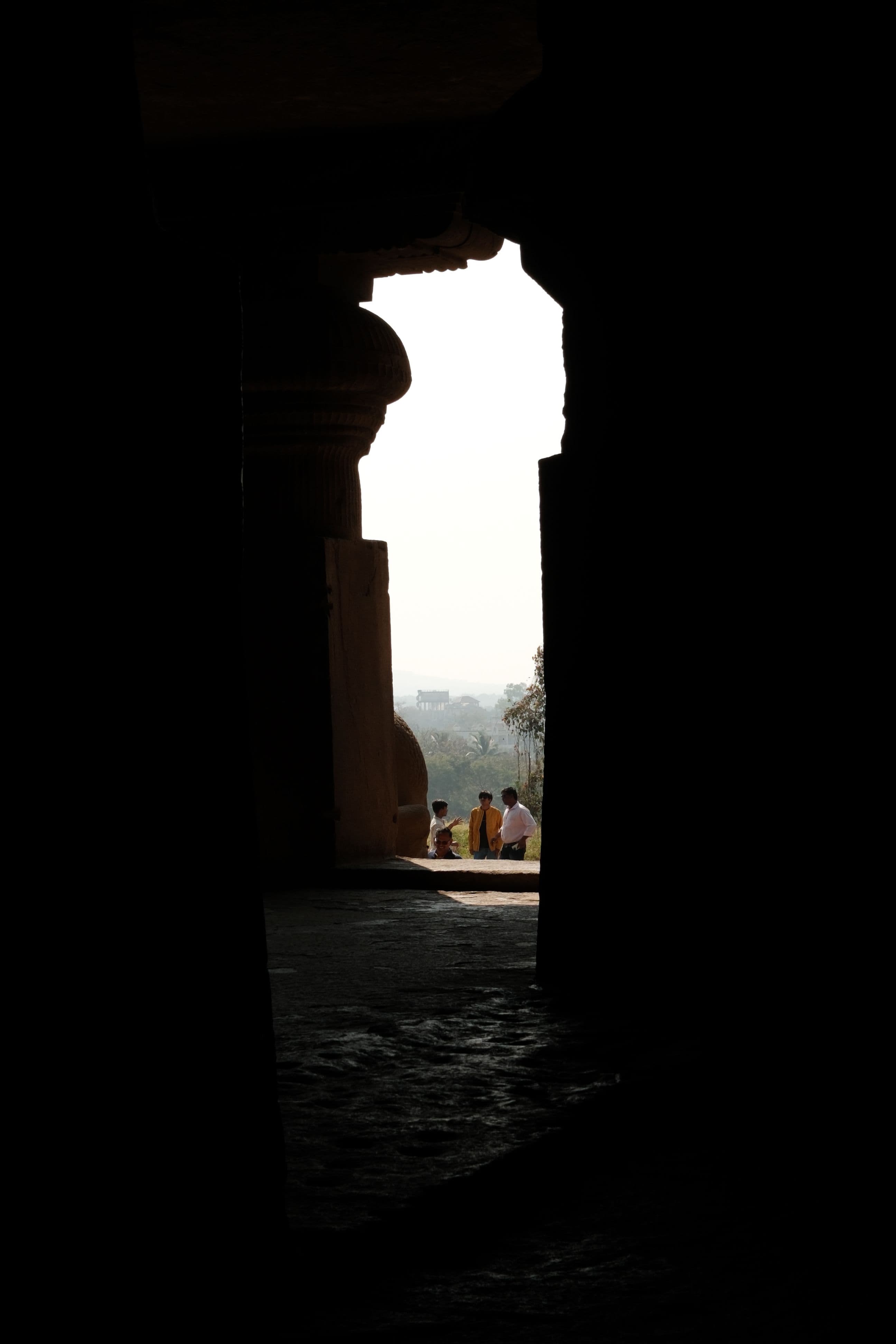 Visitors seen through a stone passageway, Ellora Caves
