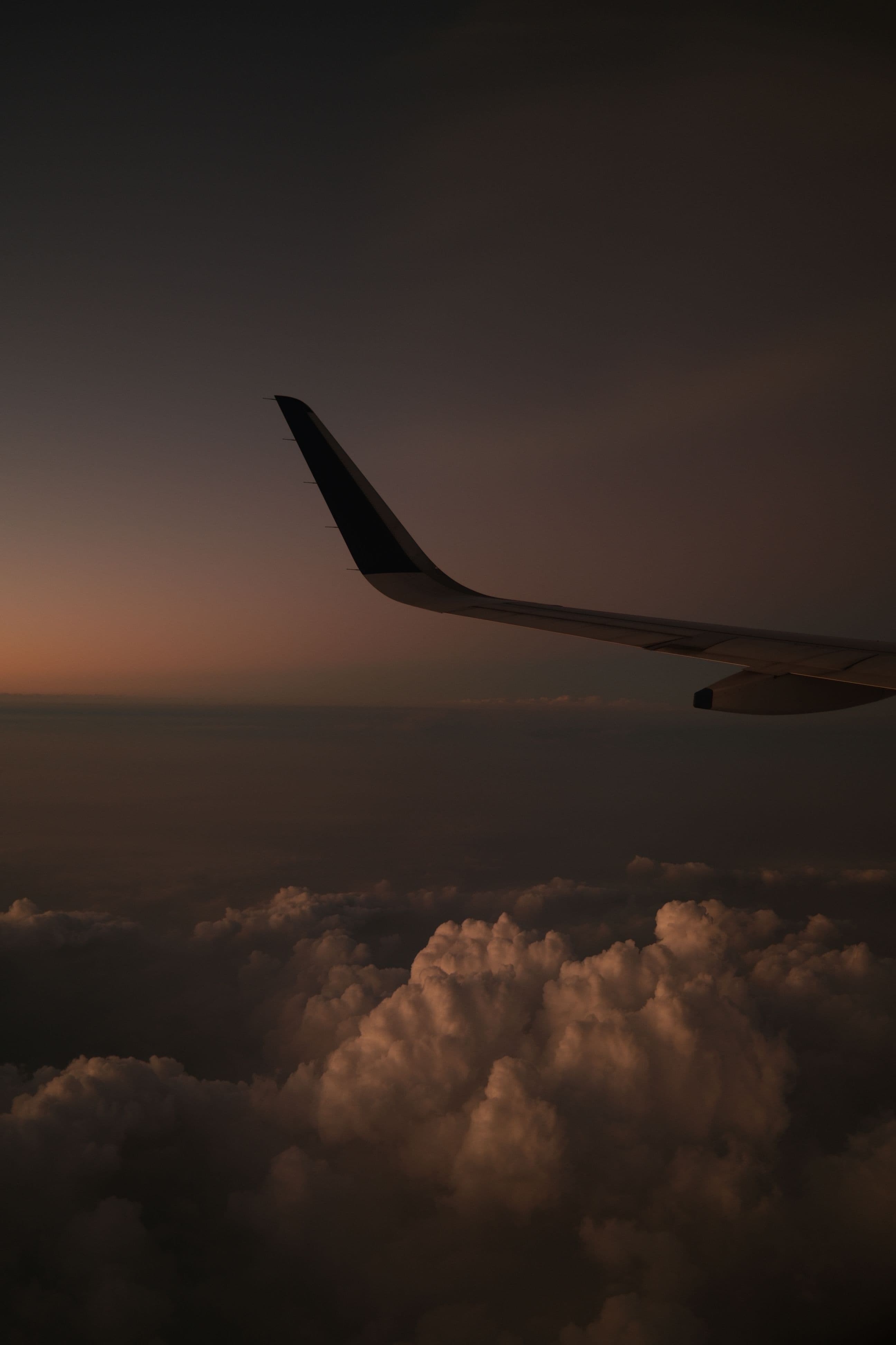 Airplane wing over clouds at dusk